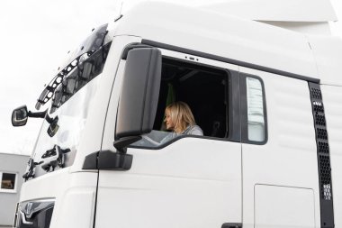 Beyaz, orta yaşlı bir kadın kamyon kullanıyor. Kamyoncu kadın işçi, ulaşım endüstrisi işgali. Yüksek kalite fotoğraf