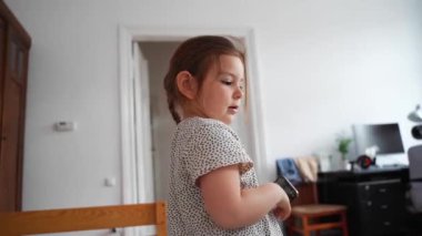 Akıllı telefonlu, komik ve tuhaf olan mutlu bir anaokulu beyaz kızı. Yüksek kaliteli FullHD görüntüler