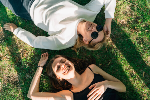 Top view of mature mother and daughter lay on the grass on sunny summer day. High quality photo