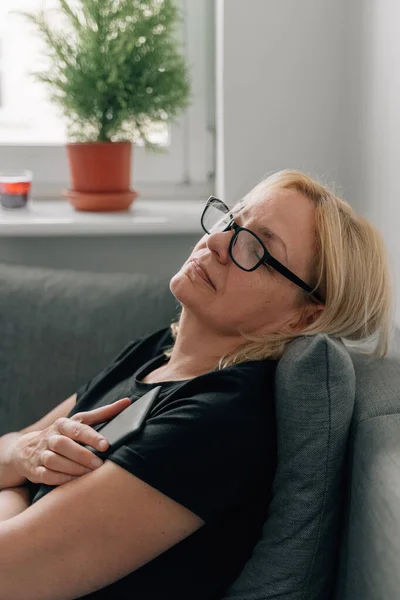 Middle age mature woman sleeping with book on the couch, home daydreaming . High quality photo