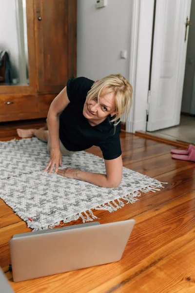 Mogen Kvinna Hemma Gör Sport Yoga Golvet Med Bärbar Dator — Stockfoto