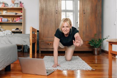 Evde laptopuyla spor yogası yapan olgun bir kadın. Yüksek kalite fotoğraf