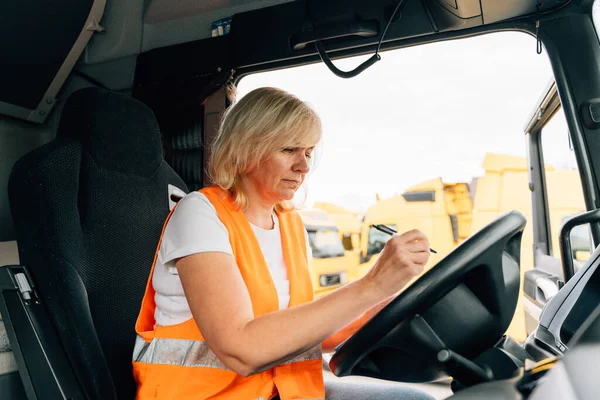 Mature woman truck driver steering wheel inside lorry cabin. Happy middle age female trucker portrait . High quality photo