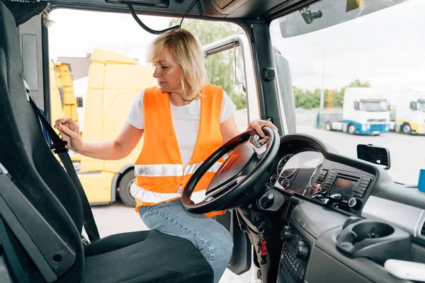 Mature woman truck driver steering wheel inside lorry cabin. Happy middle age female trucker portrait . High quality photo
