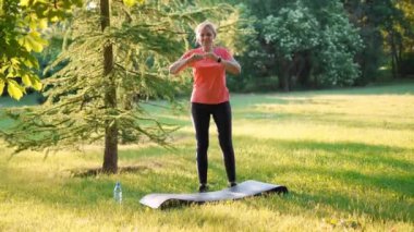 Güneşli bir yaz gününde parkta spor yapan olgun bir kadın. Yüksek kalite 4k görüntü