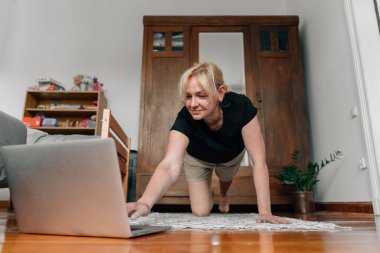 Evde laptopuyla spor yogası yapan olgun bir kadın. Yüksek kalite fotoğraf