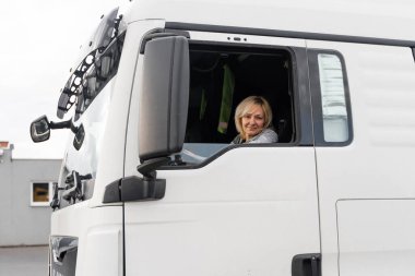 Beyaz, orta yaşlı bir kadın kamyon kullanıyor. Kamyoncu kadın işçi, ulaşım endüstrisi işgali. Yüksek kalite fotoğraf