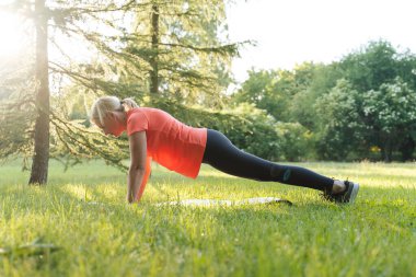 Güneşli bir yaz gününde parkta spor yapan olgun bir kadın. Yüksek kalite fotoğraf