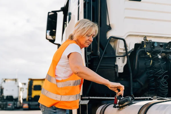 Middle age truck driver woman opens gas tank with keys . High quality photo