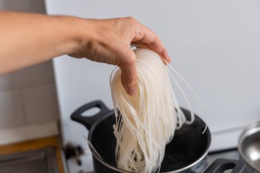 Elin pilavlı, erişteli ve tavada da mutfakta kaynar su var. Asya yemeği pişirmek. Yüksek kalite fotoğraf