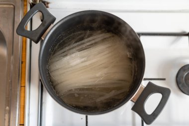 Üst manzaralı kuru erişte ve tavada kaynar su var. Asya yemeği pişirmek. Yüksek kalite fotoğraf