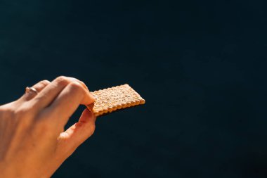 Hand with cracker outdoors on a sun light. Work snack for energy . High quality photo