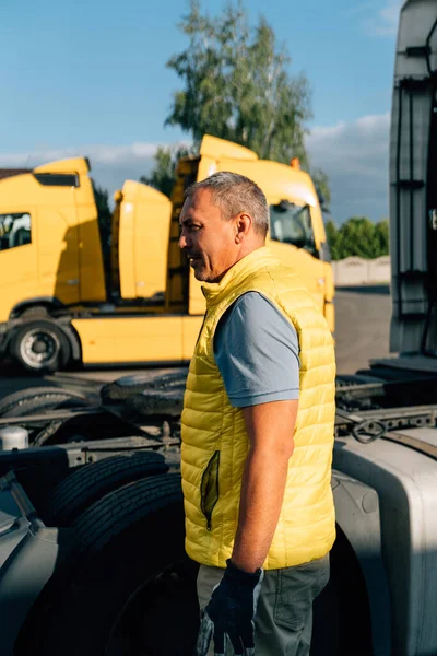 A worker smearing trailer fifth wheel coupling with lubricant oil. Semi-truck mechanical maintenance . High quality photo