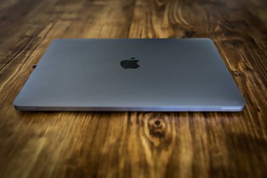 5 Aralık 2021, Cork, İrlanda - Gümüş metalik gri bir MacBook Pro dizüstü bilgisayar ahşap bir masanın üzerinde yatıyor