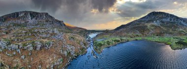 İrlanda 'nın Kerry ilçesinin Kara Vadisi' ndeki Dunloe Geçidi 'ndeki sarmal derenin üzerindeki taştan dilek köprüsünün hava panoramik görüntüsü.