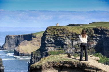 İrlanda 'nın Clare ilçesinin Burren bölgesinin güneybatı kıyısındaki Moher Uçurumlarına, deniz kayalıklarına hayranlık duyan bir kadın görülüyor.