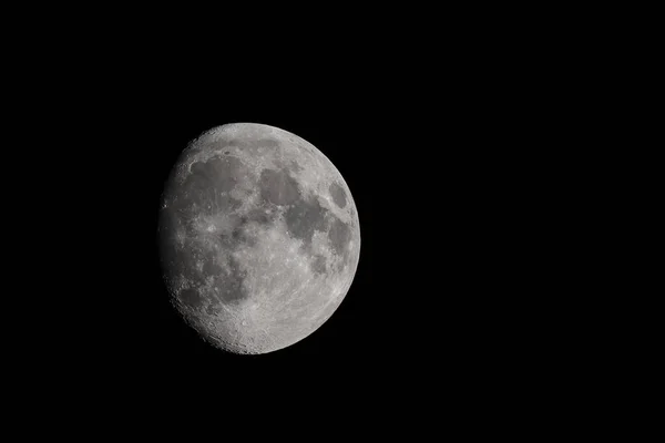 Close-up moon in waxing gibbous phase, moon surface, craters and the night sky isolated on a black background and copy space