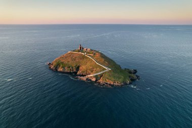 Aerial view of Ballycotton Lighthouse at sunrise from the coast of county Cork, Ireland