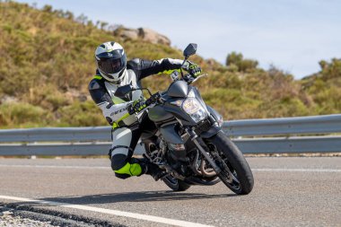 Asfaltta yatan bir motosikletli. Fotoğraf 26 Ekim 2020 'de Avila, Spai' deki Navalmoral limanında çekildi.