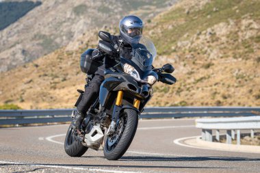 Keskin bir viraj alırken yolda motosikletli bir sürücü