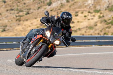 Keskin bir viraj alırken yolda motosikletli bir sürücü