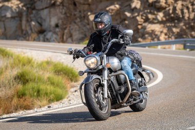 Keskin bir viraj alırken yolda motosikletli bir sürücü