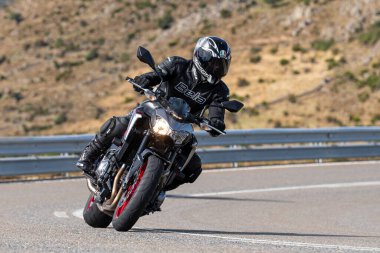 Keskin bir viraj alırken yolda motosikletli bir sürücü