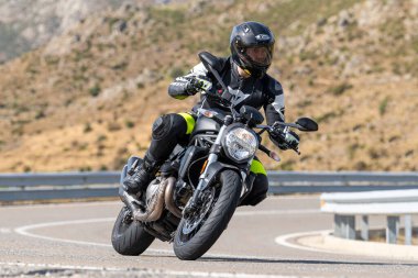 Keskin bir viraj alırken yolda motosikletli bir sürücü