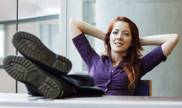 Businesswoman smiling, feet up, arms behind her head — Stock Photo, Image