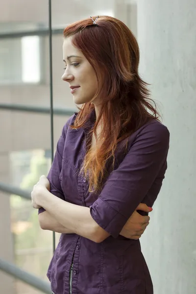 Businesswoman standing at window smling - looking down — Stock Photo, Image