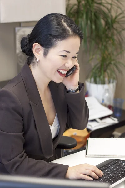 Bella asiatica donna d'affari al computer al telefono — Foto Stock