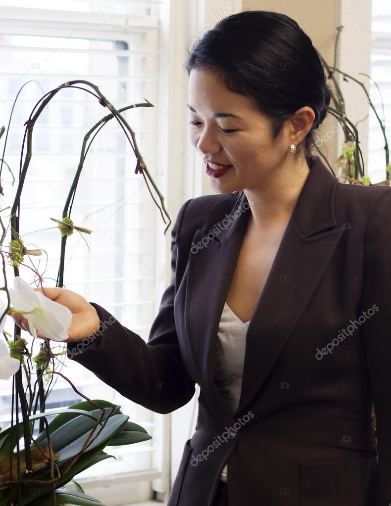 Pretty asian businesswoman admiring office plants