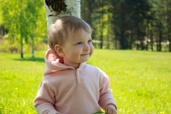 Liten flicka står vid ett träd — Stockfoto