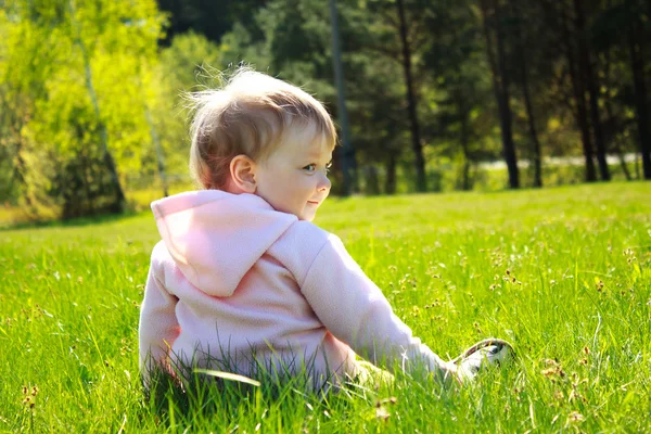 Liten flicka sitter på gräset — Stockfoto