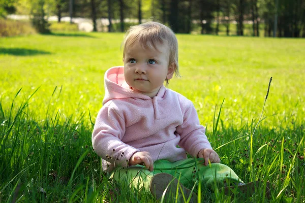 Küçük kız çimenlerde oturuyor. — Stok fotoğraf