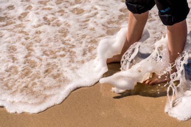 Kumlu sahilde çıplak ayaklar kot pantolonla