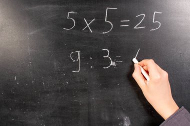 Çocuk bir tahtanın üzerine yazıp hesaplıyor.