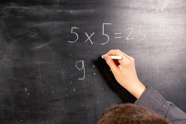 Çocuk tahtada matematik dersi veriyor.