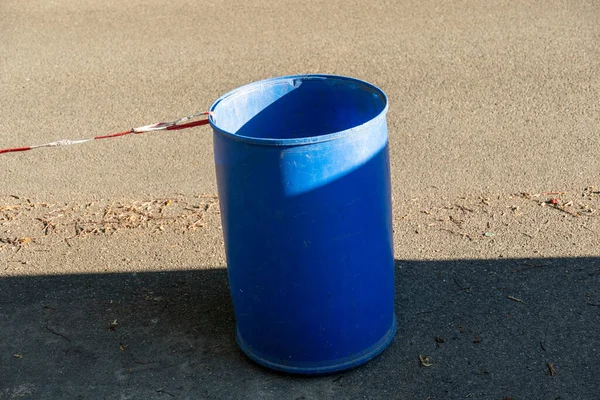 Blue plastic barrel with a barrier tape on a street