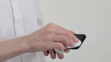 Kızın elleri kapalı ıslak bir bezle telefon ekranını silerek mikroplardan ve virüslerden cihazı temizliyor. Sağlık koruması.
