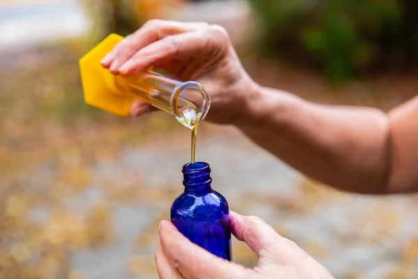 As mãos derramando um óleo essencial no frasco para injetáveis — Fotografia de Stock