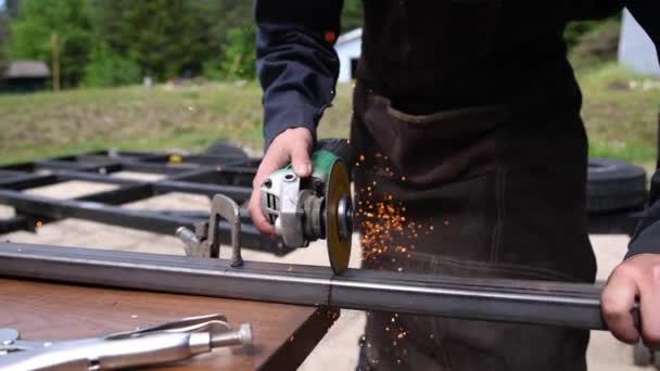 Сварщик резки железный стержень с помощью шлифовального колеса. — стоковое видео