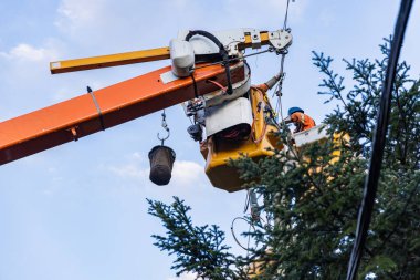 Şiddetli fırtına sonrası telleri tamir eden eklemli asansörde çalışan bir elektrik hattı teknisyeninin düşük açılı görüntüsü. Kopyalama alanı ile.