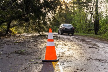 Şiddetli rüzgarlardan sonra otoyoldaki trafik konilerinin seçici odak noktası tehlikeli sürüş koşullarına ve yol engellerine neden olur. Arkaplanda bulanık trafik.