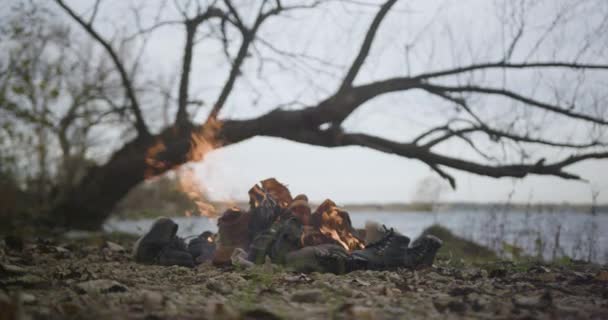 照相机慢慢地向熊熊燃烧的火堆靠近 燃烧着明亮的橙色火焰 暴露了许多旧靴子和旧鞋子作为热量的来源 — 图库视频影像