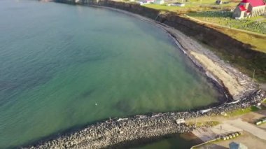 Drone, Caraquet Limanı yakınlarındaki okyanusa uzanan taşlı bir dalgakıranın üzerinde dönüyor. Fotokopi alanı olan turkuaz su ve kıyı kayalıkları.