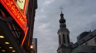 Eski Quebec, Kanada 'nın tarihi bölgesinin sokaklarında alçak görüş açısı. Renkli neon ışıklar ve akşamları bir kilise kulesi.