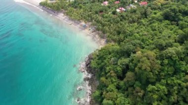 Kuşlar, Filipinler 'de turist villaları ve yemyeşil bitki örtüsü olan kıyı şeridi boyunca sakin ve berrak okyanus ve beyaz kumlu plaja bakıyor..