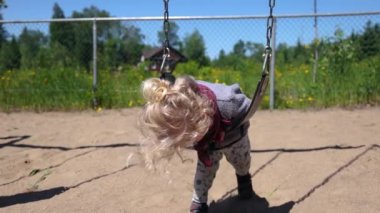 Üç yaşındaki tatlı bir çocuğun çocuk parkında sallanırken ve ileri geri sallanırken ağır çekimde karnının üzerine yattığı videoyu kapat. Uzayı kenarlara kopyala.