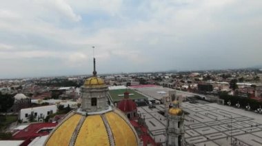 Drone clip over the golden cupola of the Basilica of Our Lady of Guadalupe ending with view of Tepeyac Hill. Catholic pilgrimage site in Mexico City.